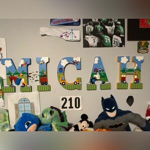 Hand-painted wooden letters for Micah with colorful transportation theme. 9”